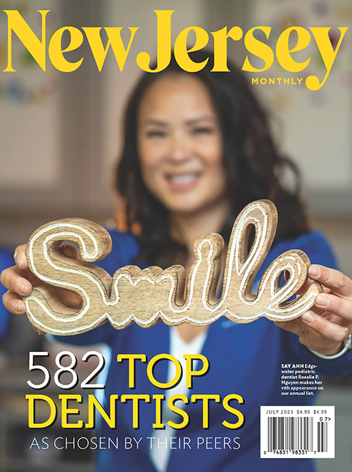 A woman holding up a sign with  Smile  written on it, surrounded by text that reads  692 Top Dentists 581 New Jersey.