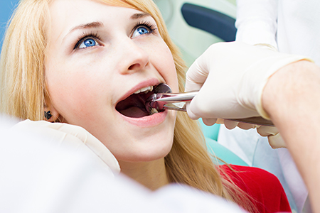 The image depicts a woman in a dental chair undergoing a dental procedure with a dental professional assisting her.